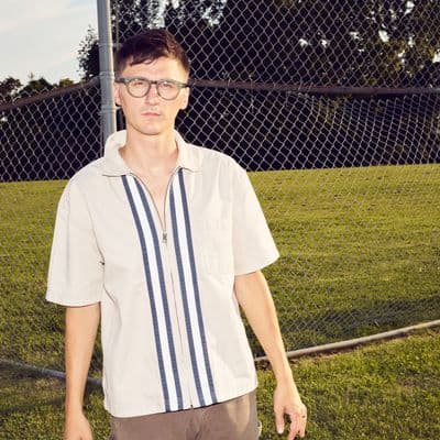 Ben Foster looking at camera in front of a fence